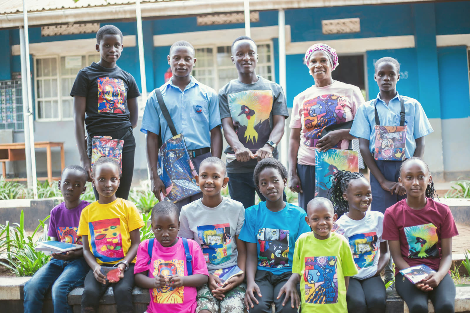 Children standing in front of a wall of their own paintings