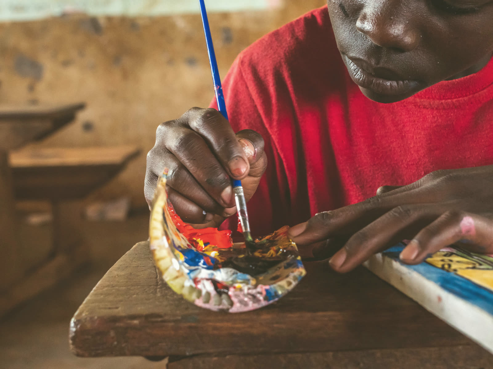 Children painting at wooden desks in a sunlit classroom